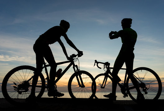 Silhouettes of Cyclists on bicycle at the ocean in the sunset sc