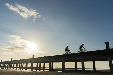 Silhouettes of cyclists with bicycles on the bridge warm tone