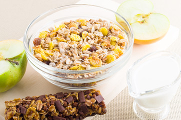 Muesli in a glass bowl, milk and fresh apple