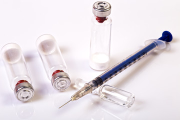 Pen medical syringe, One ampule with saline and vials with dry human hormone drug powder, forbidden sportsmen doping. Blue syringe and vials lying on white background. Close up image.
