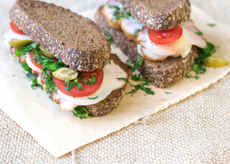 Fresh sandwich on a wooden table with a piece of burlap.