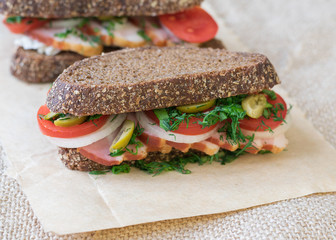 Fresh sandwich on a wooden table with a piece of burlap.