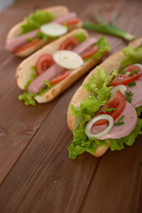sandwich with sausage and vegetables on a wooden table