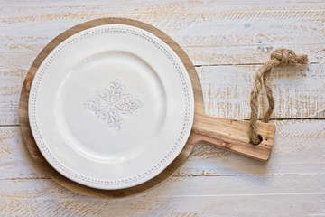 White vintage empty plate on round cutting board, white plank wood background, Provence style,...