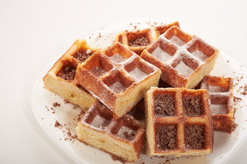 Belgian waffles with grated chocolate and icing on a white plate