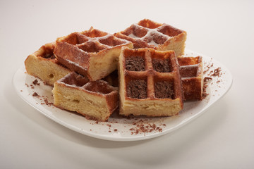 Belgian waffles with grated chocolate and icing on a white plate