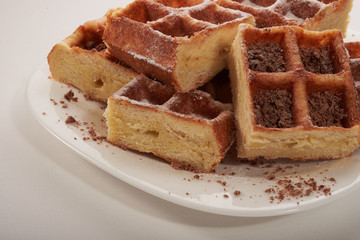 Belgian waffles with grated chocolate and icing on a white plate