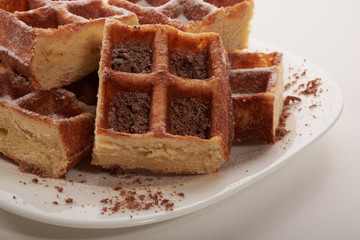 Belgian waffles with grated chocolate and icing on a white plate