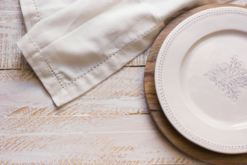 White vintage empty plate on round cutting board, linen cloth over white wood background, Provence...