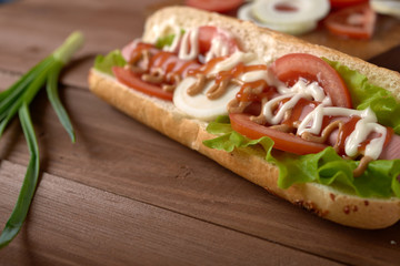sandwich with sausage and vegetables on a wooden table