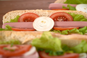 sandwich with sausage and vegetables on a wooden table