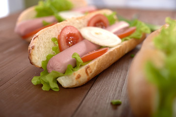 sandwich with sausage and vegetables on a wooden table