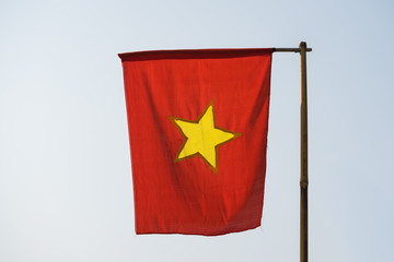 Still Vietnamese flag on wooden flagpole made of bamboo dry tree, in foggy morning