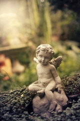 Fototapeta na wymiar Cupid sculpture in garden, background for Valentine's day. color toned.