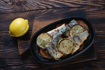 Baked sea bass fillet with tomatoes and lemon in a frying pan