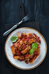 Plate with italian ziti over black wooden background, above view