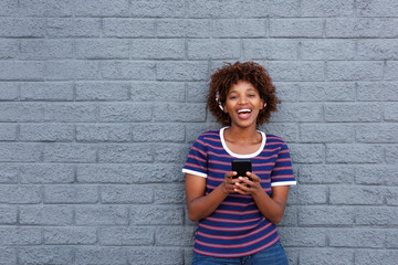 african woman smiling and holding cell phone