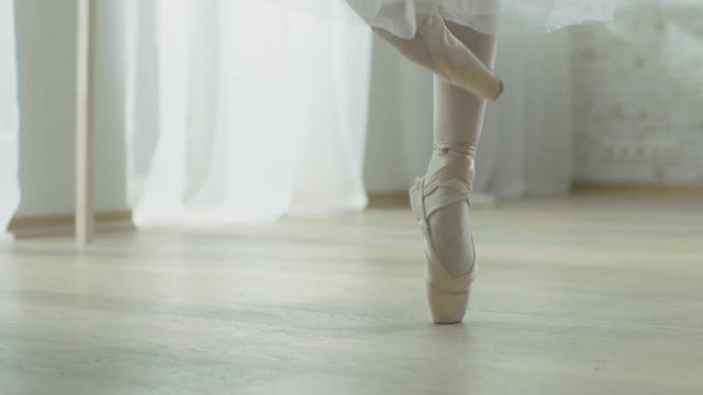 Close-up Shot of Ballerina's Legs. She Dances on Her Pointe Ballet Shoes. She's Wearing White Tutu Dress. Shot in a Modern Studio. In Slow Motion.  Shot on RED EPIC-W 8K Helium Cinema Camera.