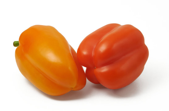 Red and orange bell pepers in horizontal position on white backg