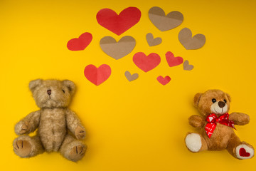 A lot of hearts and two teddy bears on the yellow background