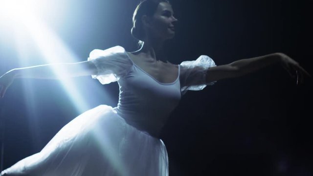  Mid Shot of a Beautiful Young Ballerina Dancing Gracefully in the Spotlight, Darkness Around Her. Shot on RED EPIC-W 8K Helium Cinema Camera.