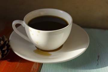 A hot morning coffee served in a beautiful cutlery with delicious brown bread on an orange and light cyan old wooden table.