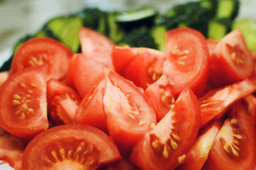 sliced tomatoes and cucumbers lie on a plate, close-up