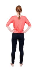 back view of standing young beautiful  blonde woman in jeans.