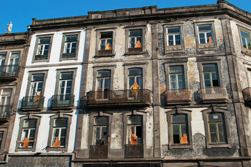Fototapeta na wymiar Portogallo, 26/03/2012: i dettagli dello skyline di Porto, la seconda città più grande del paese, con vista di un edificio abbandonato con sagome arancioni di cartone sui balconi