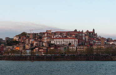 Fototapeta na wymiar Portogallo, 26/03/2012: barche al tramonto e lo skyline di Porto con vista del fiume Douro tra le città di Porto e Vila Nova de Gaia