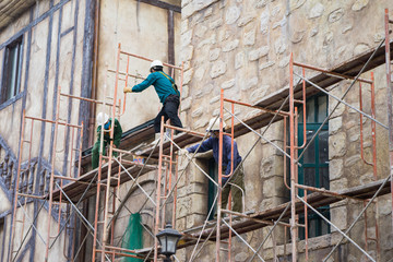Workers with no protection belt fixed on scaffold at construction site