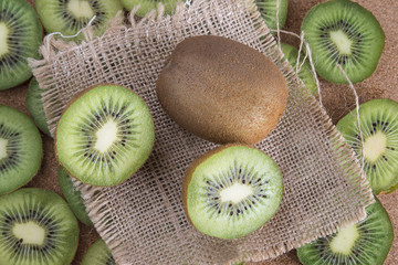 sliced kiwifruit on sackcloth napkin on old wooden background © stsvirkun
