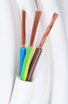 Electrical power cable close up. IEC standard color code. Cross-section with cable jacket, wire insulations in brown, blue and yellow-green color with flexible stranded copper wires. Macro photo.