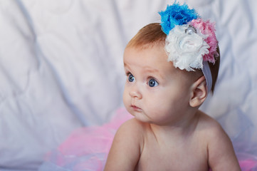 Newborn baby girl wearing a white crocheted crown, ballerina tutu, and ballet slippers. She is on pink rose ribbon fabric. © gal2007
