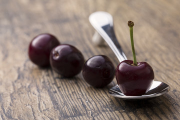 Close-up of cherries in a silver spoon on brown background