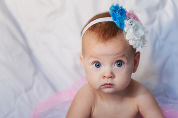 Newborn baby girl wearing a white crocheted crown, ballerina tutu, and ballet slippers. She is on pink rose ribbon fabric. © gal2007