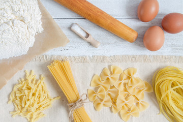Pasta and wheat spikelets on a white wooden background