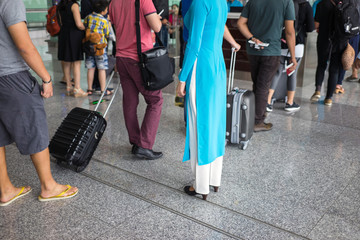 Queue of people in Noi Bai airport, Vietnam. Focus on female staff wearing Vietnamese long dress Ao Dai