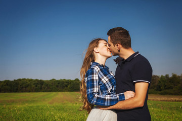 beautiful couple standing in field and kisses
