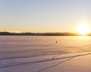 A person walking on icy lake on a sunny winter day