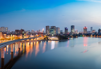 Fototapeta premium Widok z lotu ptaka na panoramę Hanoi w okresie zmierzchu, z jeziorem Dong Da i budowaną kolejką Cat Linh - Ha Dong