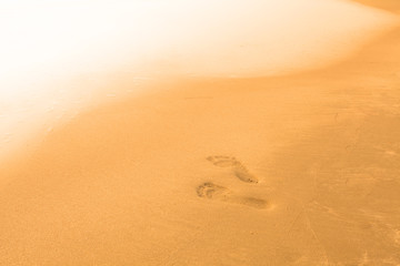 Blurry background of beach and sea waves with feet stamp on sand, Vintage color style.