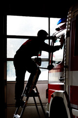 Fototapeta na wymiar Firefighter cleans firetruck. Maintenance of fire equipment. Life at the fire station.