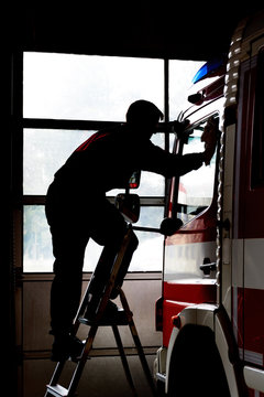 Firefighter cleans firetruck. Maintenance of fire equipment. Life at the fire station.