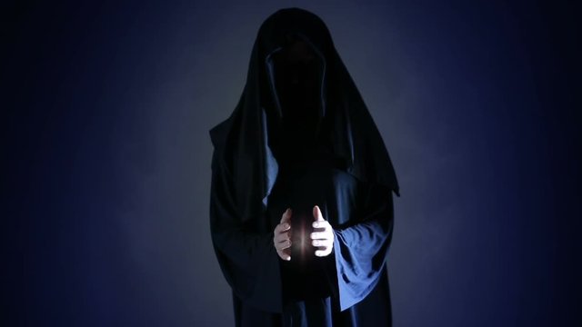 Halloween. Powerful witch or wizard with fireball in hands. Ball from fire burns