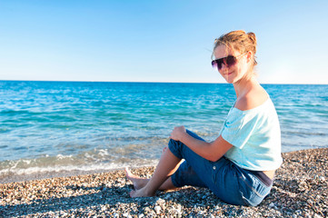Fototapeta na wymiar Young beautiful teenage girl realxing on Mediterranean Sea pebbl