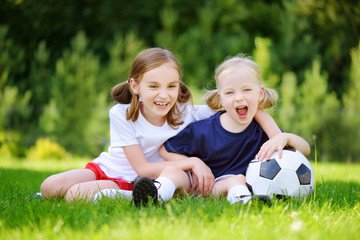 Fototapeta premium Two cute little sisters having fun playing a soccer game