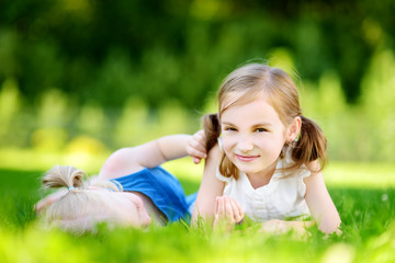 Obraz premium Two cute little sisters having fun together on the grass