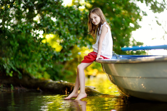 Cute little girl having fun in a boat by a river