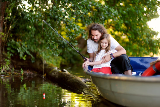 Cute little girl and her father having good time together in a boat by a river